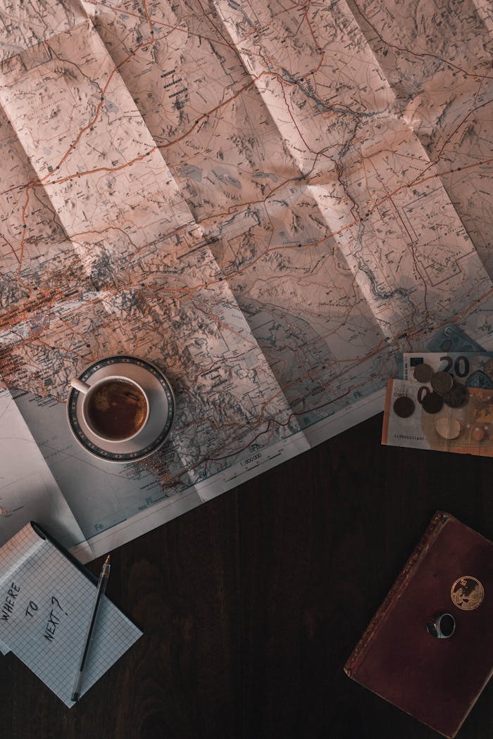 Home Flat lay of map, coffee, coins, and notebook for travel planning.