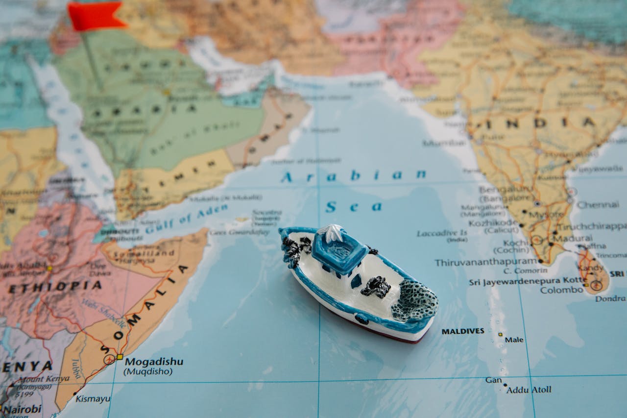 Home Close-up of a toy boat placed on the Arabian Sea section of a world map depicting regions around India.